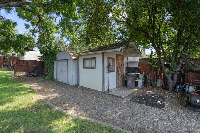 a backyard of a house with lots of plants and large tree