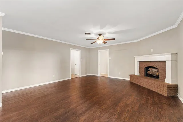 a view of an empty room with wooden floor and fireplace