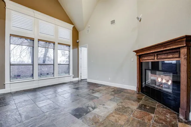 a view of an empty room with wooden floor and fireplace