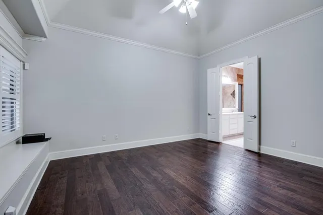 an empty room with wooden floor and a ceiling fan