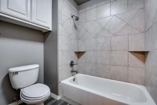 a white toilet and tub sitting next to a white cabinet