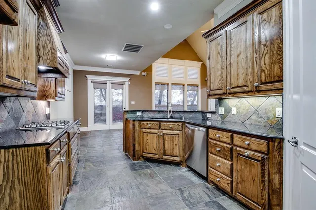 a kitchen with stainless steel appliances granite countertop a stove a sink and a refrigerator