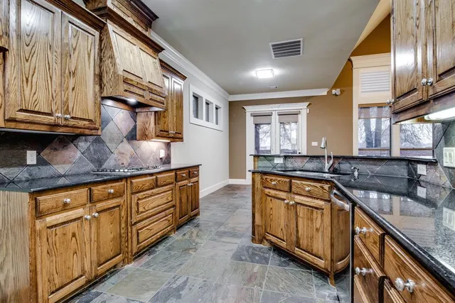 a kitchen with stainless steel appliances granite countertop a sink a stove and a wooden cabinets