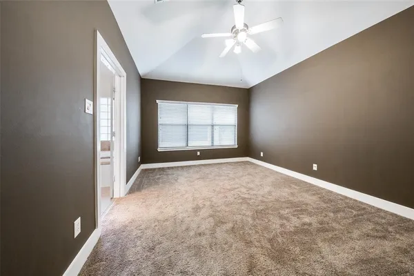 an empty room with windows and chandelier fan