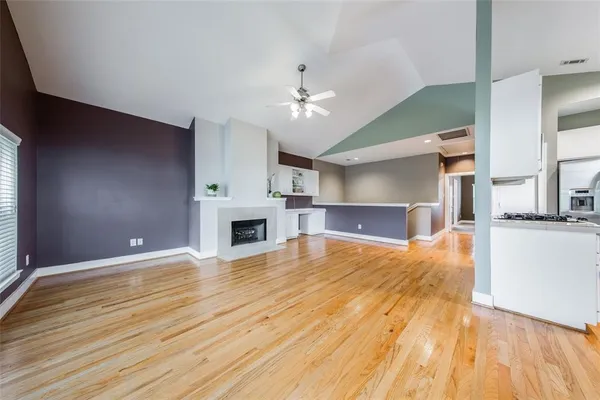 a view of empty room with kitchen and fireplace