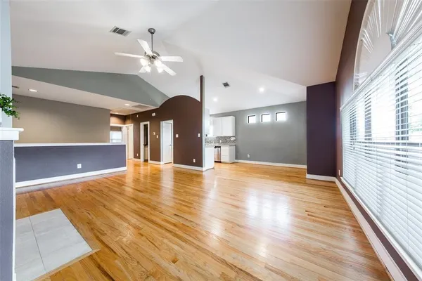 a view of an empty room with window and wooden floor
