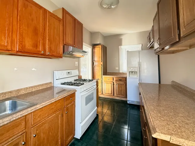 a kitchen with granite countertop a sink a stove and refrigerator