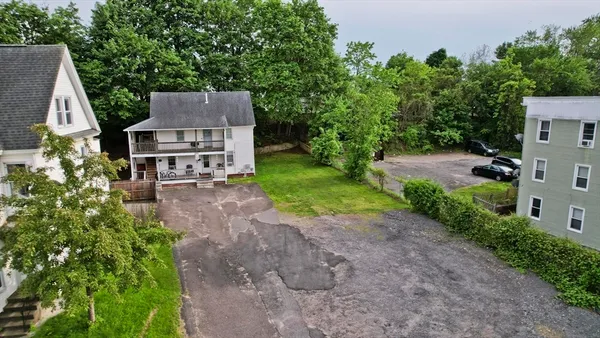 a view of a house with a small yard and large tree