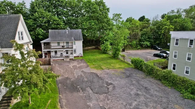 a view of a house with a small yard and large tree