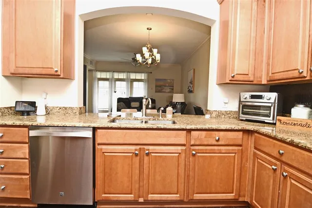 a room with stainless steel appliances granite countertop a refrigerator and a wooden floor