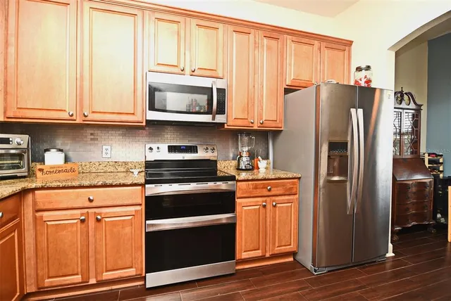 a kitchen with stainless steel appliances granite countertop a sink and cabinets with wooden floor
