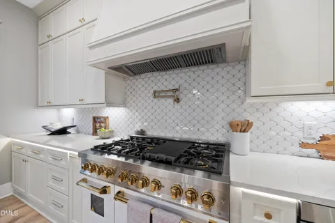 a view of a room with kitchen island stainless steel appliances wooden floor and chandelier