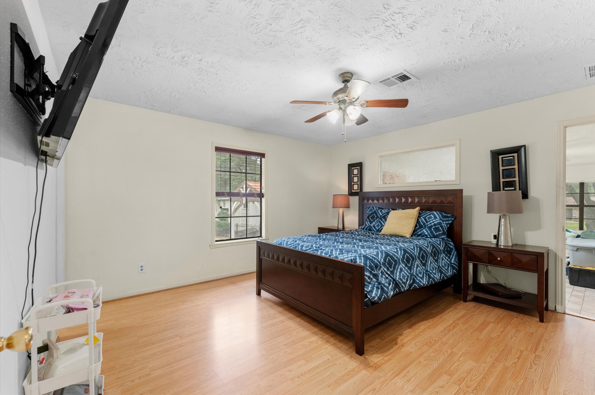 22634 Park Road Tomball, TX 77377 - Photo 16 of 29 Spacious bedroom featuring laminate flooring, a ceiling fan, and abundant natural light from large windows, creating a cozy and inviting atmosphere.