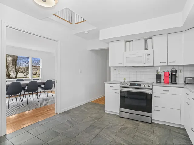 a kitchen with granite countertop a stove a white cabinets and chairs