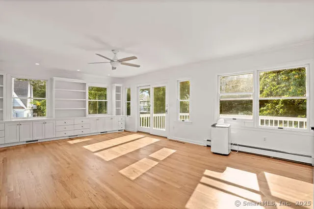 a view of an empty room with a window and wooden floor