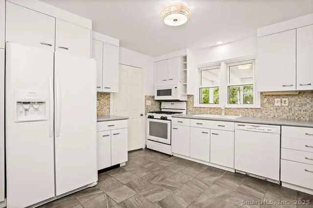a kitchen with white cabinets and white appliances