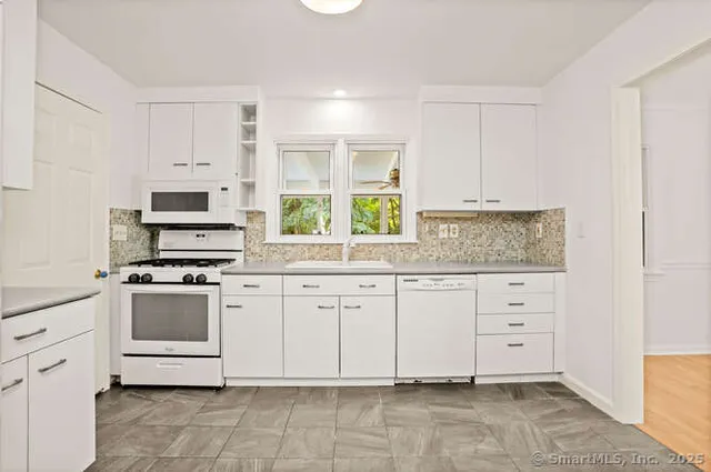a kitchen with granite countertop white cabinets and white stainless steel appliances