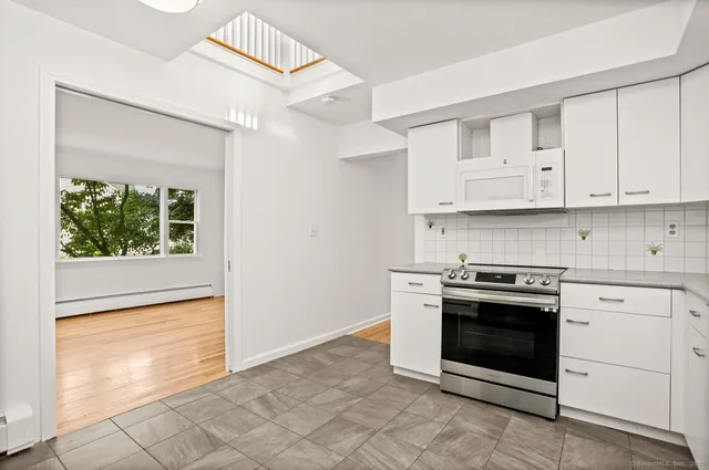a kitchen with granite countertop white cabinets and white appliances