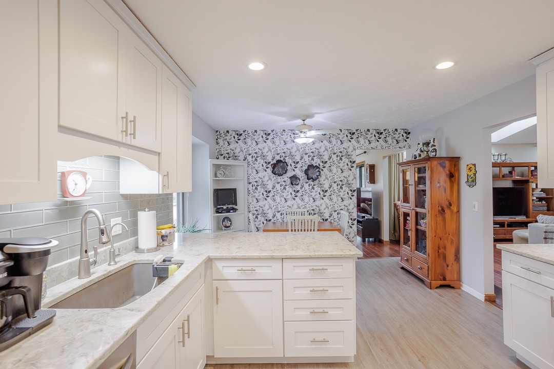 540 Basil Street Springboro, OH 45066 - Photo 10 of 32 This modern kitchen features crisp white cabinetry and light granite countertops, extending into a spacious dining area.