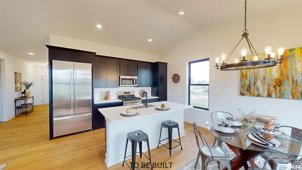 a open kitchen with stainless steel appliances granite countertop a dining table chairs and refrigerator