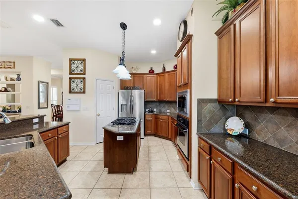 a kitchen with granite countertop a sink a counter top space appliances and cabinets