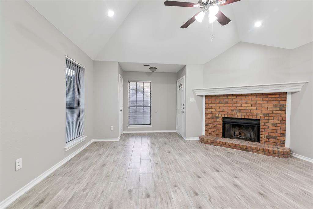 304 Moore Creek Road, Unit 300 Hurst, TX 76053 - Photo 2 of 17 Living room featuring a brick fireplace with a white mantel, vaulted ceilings, a ceiling fan, and wood-finish flooring