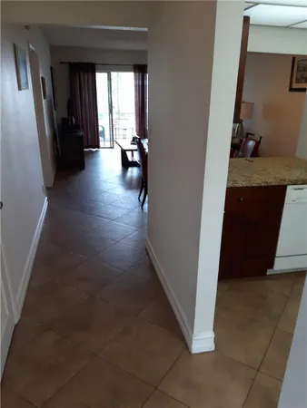 a view of a hallway to a livingroom with wooden floor and furniture