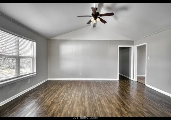 a view of an empty room with a window and wooden floor