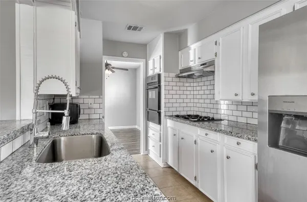 a kitchen with stainless steel appliances granite countertop a sink stove and refrigerator