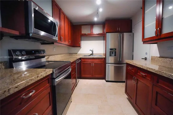a kitchen with stainless steel appliances granite countertop wooden cabinets a stove top oven a sink and dishwasher