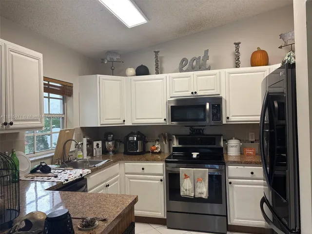 a kitchen with stainless steel appliances granite countertop a stove a sink and a microwave