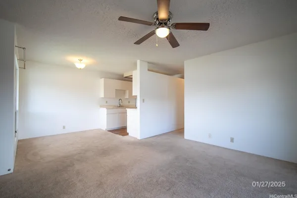 a view of a big room with windows and ceiling fan