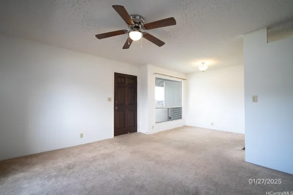 an empty room with chandelier fan and windows