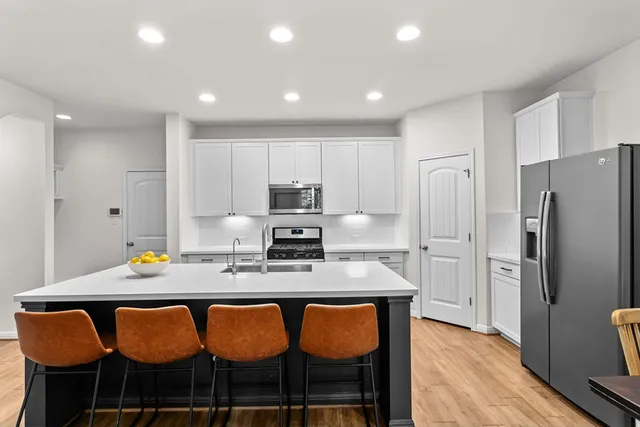 a kitchen with stainless steel appliances granite countertop a table chairs sink and refrigerator