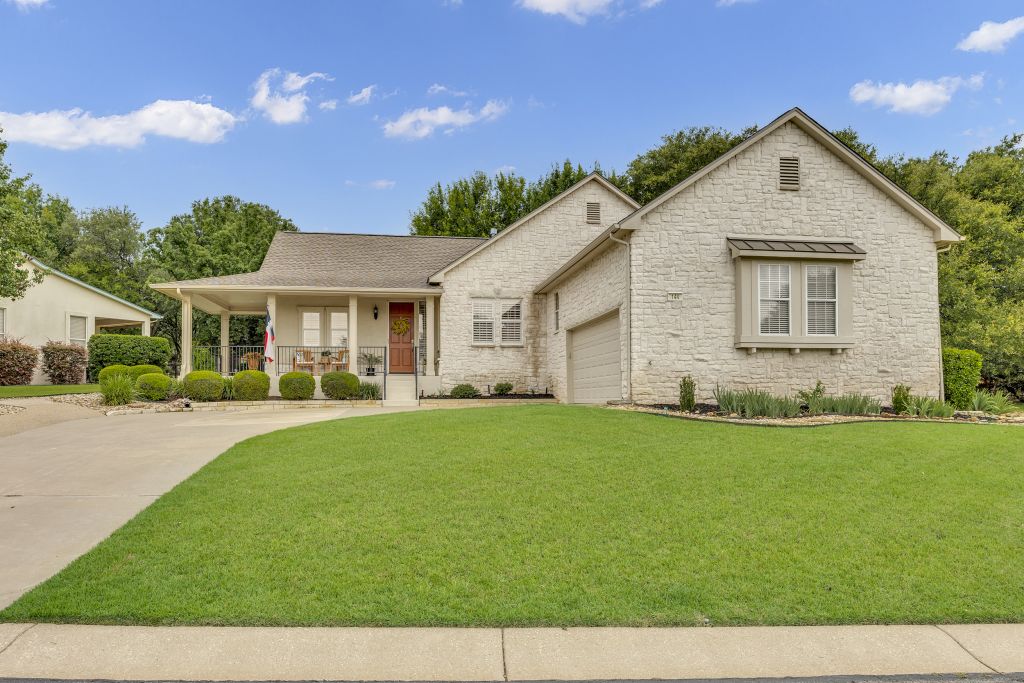 144 Cattle Trail Way Georgetown, TX 78633 - Photo 31 of 37 Well-maintained lawn with a stone facade home and welcoming covered front porch.