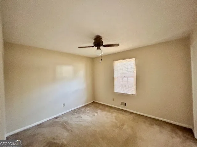 an empty room with a window and a ceiling fan