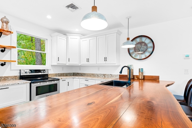 21 Lake Road Newton, NJ 07860 - Photo 11 of 18 a kitchen with a stove a sink a kitchen island with a dining table and chairs