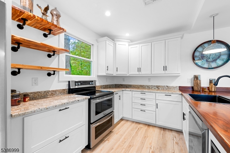 21 Lake Road Newton, NJ 07860 - Photo 9 of 18 a kitchen with a stove white cabinetry a sink and dishwasher with wooden floor