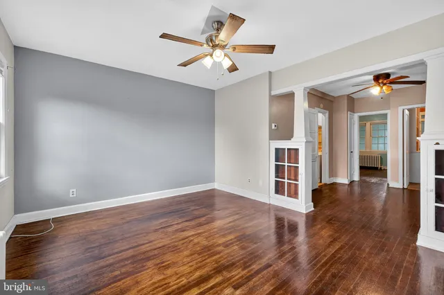 an empty room with wooden floor and ceiling fan