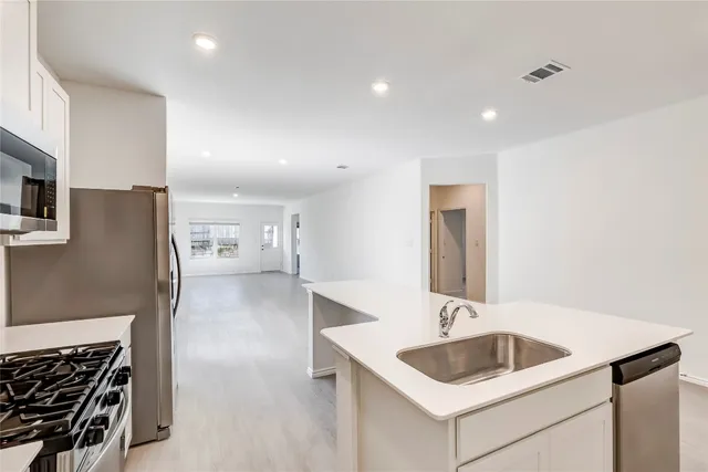 a kitchen with a sink and a refrigerator with wooden floor