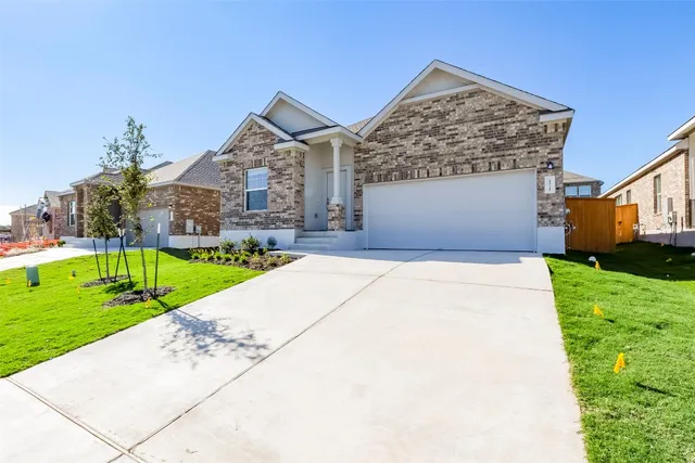 a front view of a house with a yard and potted plants