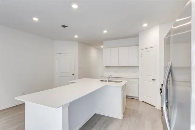 a kitchen with a refrigerator a sink and white cabinets