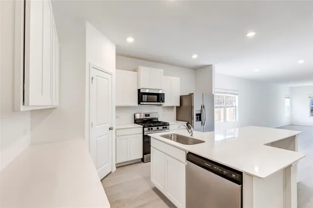 a kitchen with a sink a stove a refrigerator and white cabinets