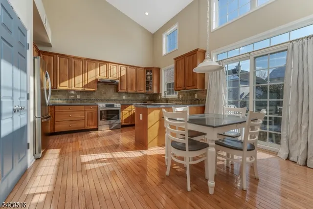 a kitchen with stainless steel appliances granite countertop a stove top oven a dining table and chairs with wooden floor