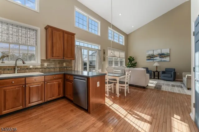 a kitchen with stainless steel appliances granite countertop a refrigerator a sink dishwasher a stove and white countertops with wooden floor