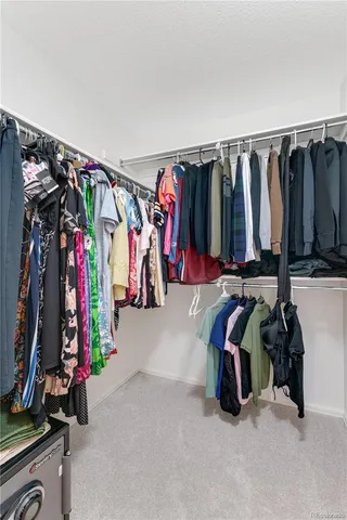 a view of walk in closet with clothes and shoes