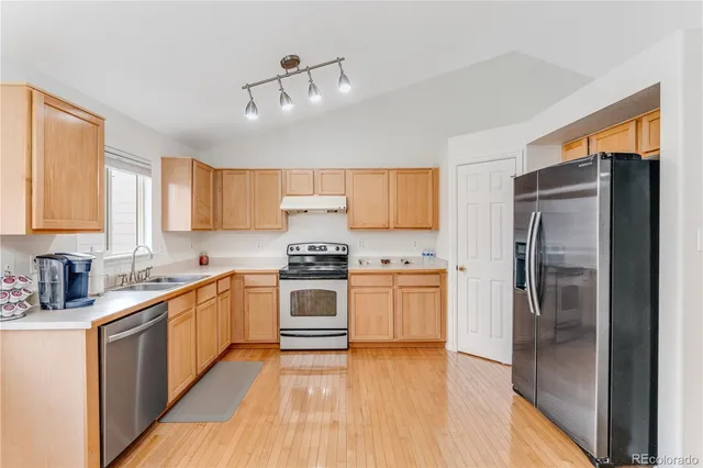 a kitchen with stainless steel appliances granite countertop a refrigerator a stove and a sink