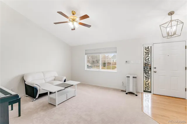 an empty room with ceiling fan and windows
