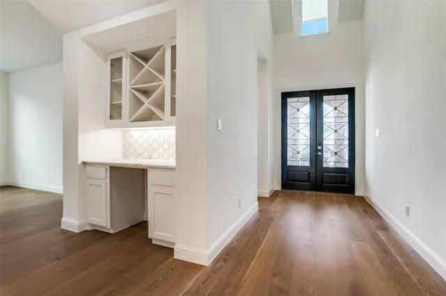 an empty room with wooden floor cabinet and windows