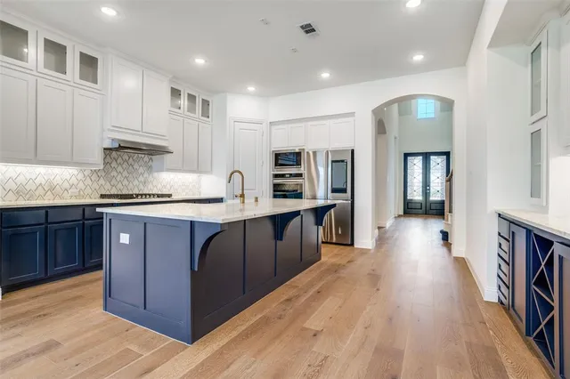 a kitchen with stainless steel appliances granite countertop a refrigerator a sink dishwasher and wooden cabinets with wooden floor